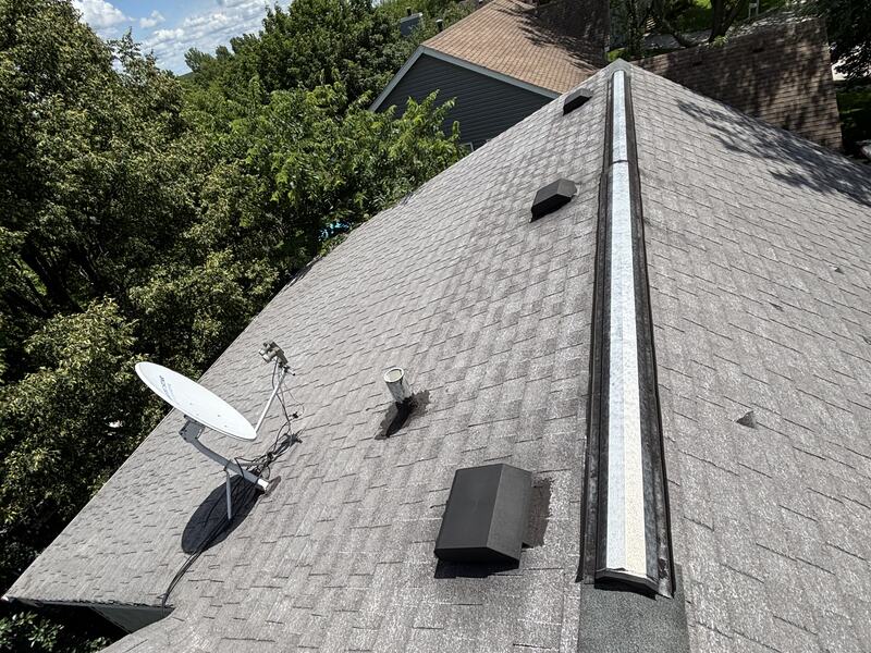 Gray shingle roof with new ridge vent viewed from the peak against a blue sky