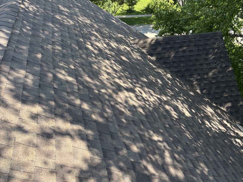 Brown architectural shingle roof slope with a neighboring house visible beyond