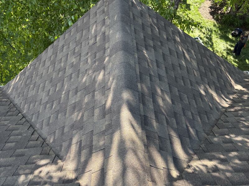 Hip roof ridge in dappled shade showing evenly laid architectural shingles
