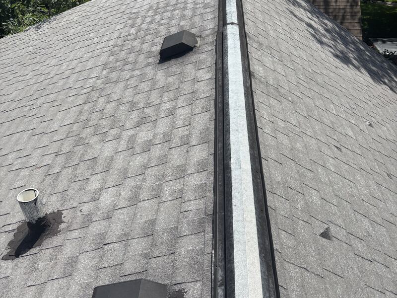 New aluminum ridge vent installed along the peak of a gray asphalt shingle roof